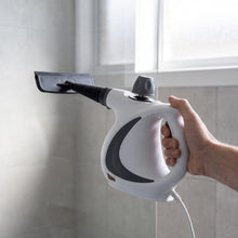 The Sanora steam cleaner with the squeegee head held against a glass shower screen